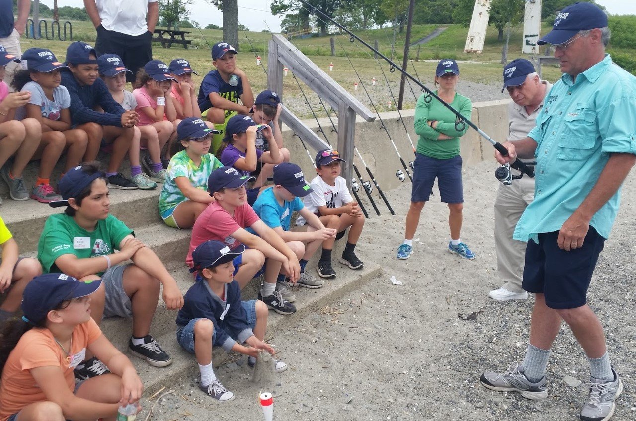 HAPPY CAMPERS: Richard Reich, RISSA Youth Fishing Camp Director, and RISAA volunteers, instruct campers on how to use a spinning rod and reel. (Submitted photos)